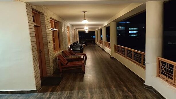 A corridor with wooden benches, brick walls, and large windows. - Fabhotel Mahavir (Manali)