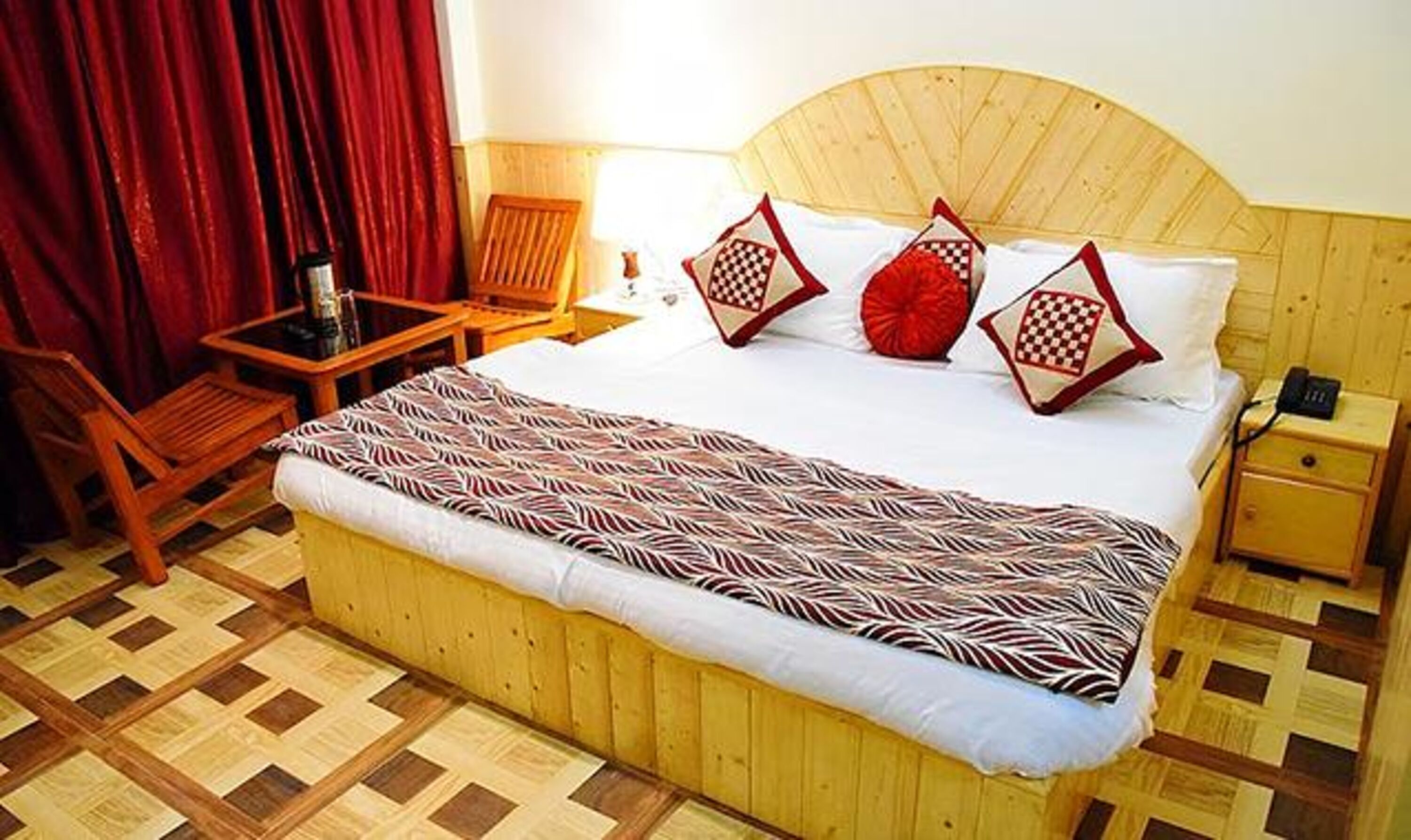 Een hotelkamer met een houten bed, nachtkastje van hout, een stoel en een klein tafeltje.