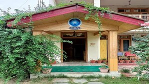 A wooden building with a red roof and a circular emblem above the entrance. - Fabhotel Mahavir (Manali)