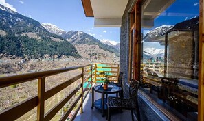 A balcony with a view of snow-capped mountains and a town below. - Fabhotel La Kailasha Regency (Manali)