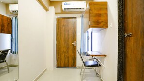 A hallway with a wooden door, a mirror, a chair, and a small table. - Fabhotel Royal Paradise (Surat)