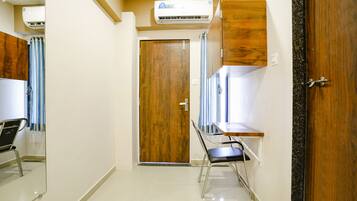 A hallway with a wooden door, a mirror, a chair, and a small table.