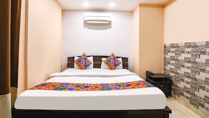 A hotel room with a bed, an air conditioner, a telephone, and a small table. - Fabhotel White Palace (Kolkata)