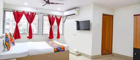 A bedroom with a bed, a ceiling fan, a TV, and a window with curtains.