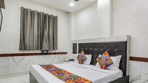 A hotel room with a bed, a telephone, a curtain, and a wall with a decorative pattern. - Fabexpress Myraa (Mathura)
