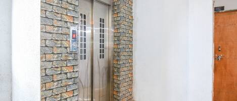 Egy lift, melynek homlokzata kőből készült, és digitális kijelzővel van felszerelve.