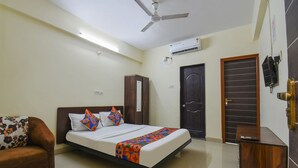 A bedroom with a bed, a wardrobe, a desk, a sofa, and a door with a window. - FabHotel Shri Krishna (Paud)