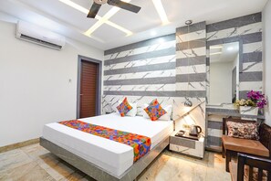 A modern bedroom with a bed, bedside table, and a mirror. - Fabhotel Prime Mansa (Kanpur)