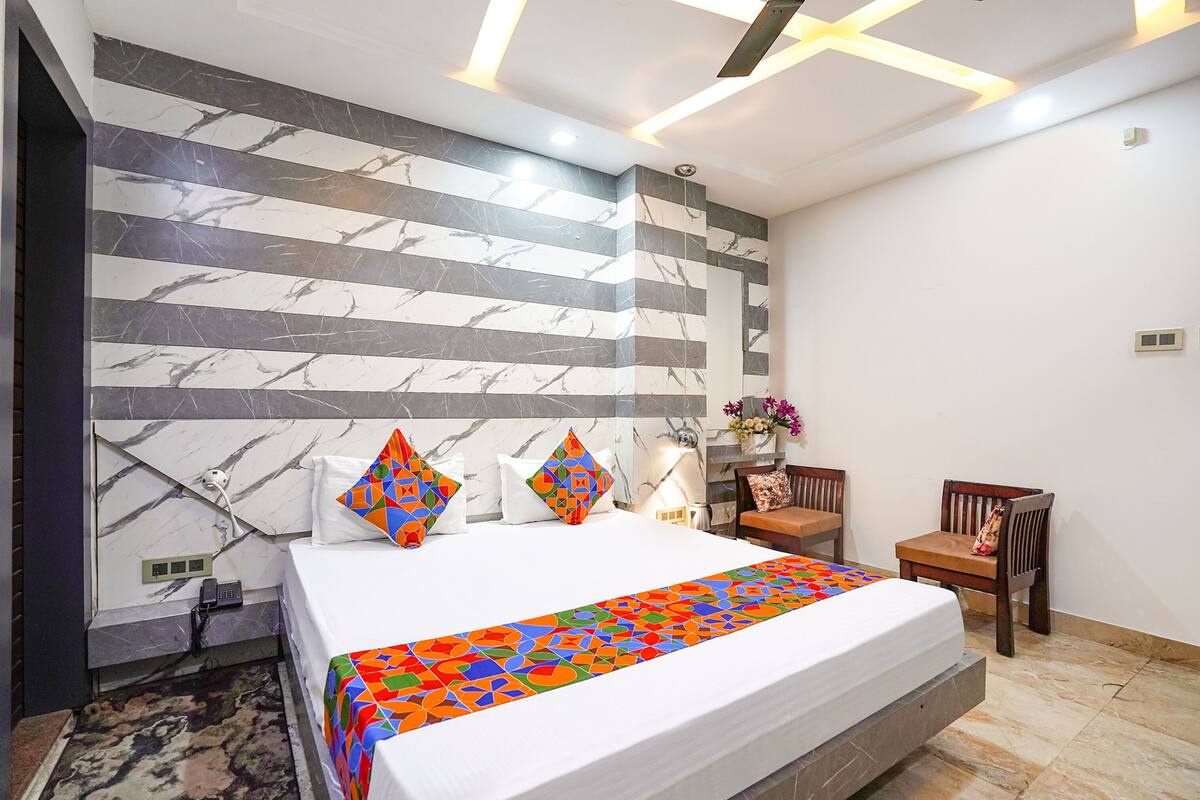 Una habitación de hotel con una cama grande, un muro con diseño de mármol, un escritorio pequeño y una silla.