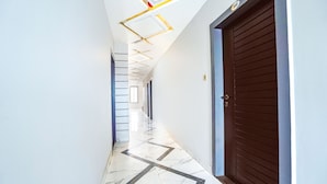 Un pasillo moderno con suelo de estampado geométrico, una puerta de madera e iluminación empotrada en el techo.