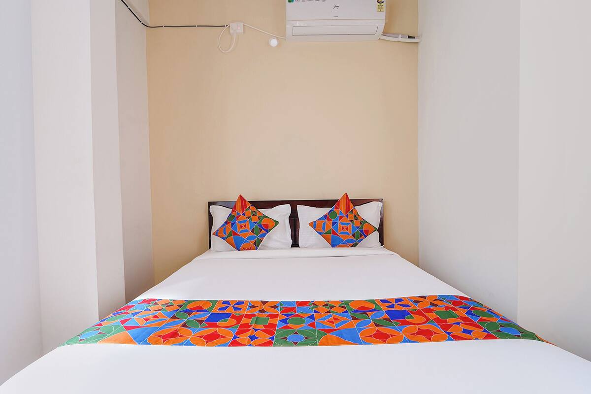 A bed with a colorful geometric-patterned bedspread and two pillows with a similar design.
