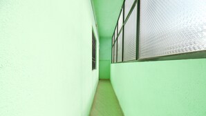 A narrow hallway with green walls and a tiled floor. - Fabexpress Ashoka Lodging (Chhatrapati Sambhajinagar)