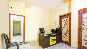 A hotel reception desk with a 'fab hotels' sign, a chair, and a door with decorative wood paneling. - Fabexpress Ashoka Lodging (Chhatrapati Sambhajinagar)