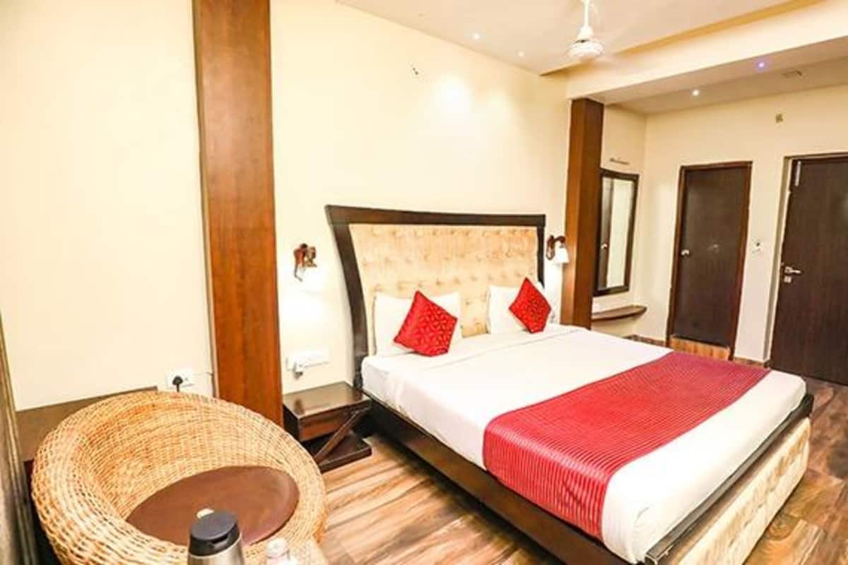 A hotel room with a large bed, a bedside table, a chair, and two doors.