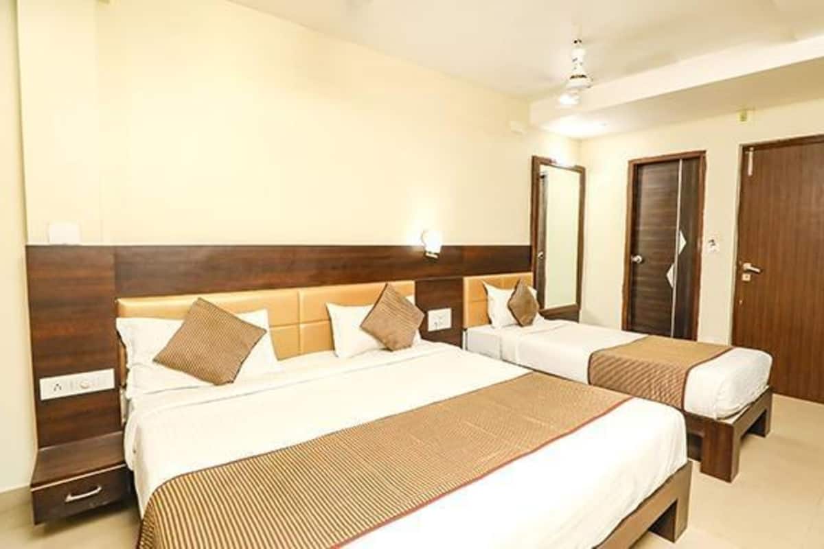 A hotel room with two beds, wooden headboards, and a nightstand with a lamp.