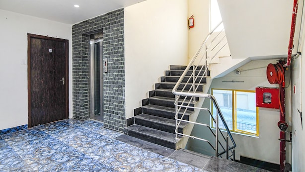 A staircase with metal railings, a fire extinguisher, and a window with a view of the outside. - Fabhotel Grand Hazra Inn (Kolkata)