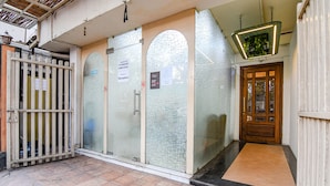 A reception area with a glass door, a wooden door, and a metal gate. - Fabhotel Grand Hazra Inn (Kolkata)