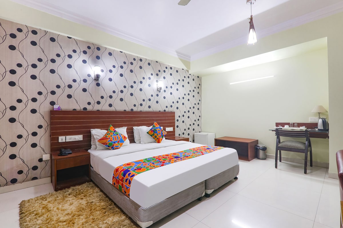 Um quarto com cama, mesas de cabeceira, escrivaninha e uma cadeira.