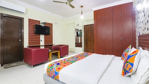 A hotel room with a bed, a desk, a chair, a TV, and a wardrobe. - Fabhotel Royal Ville (Patna)