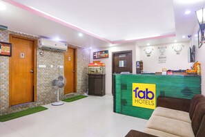 A hotel lobby with a reception desk, a clock, and a fish tank. - Fabhotel Royal Ville (Patna)