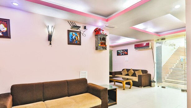 A modern living room with a brown sofa, a coffee table, and a dining area with a table and chairs. - Fabhotel Royal Ville (Patna)