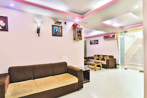A modern living room with a brown sofa, a coffee table, and a dining area with a table and chairs. - Fabhotel Royal Ville (Patna)