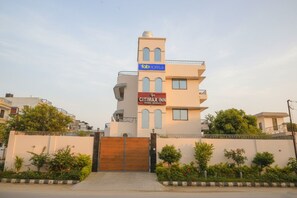 Un edificio de varios pisos con una entrada porticada, un letrero que dice 'CITIMAX INN' y un letrero de 'fabHOTELS' en la parte superior.
