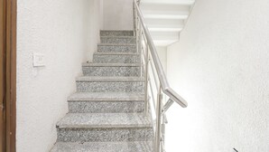 A staircase with granite steps and a metal handrail, leading to a landing with a white ceiling. - Fabexpress Baba'S Inn (New Delhi)