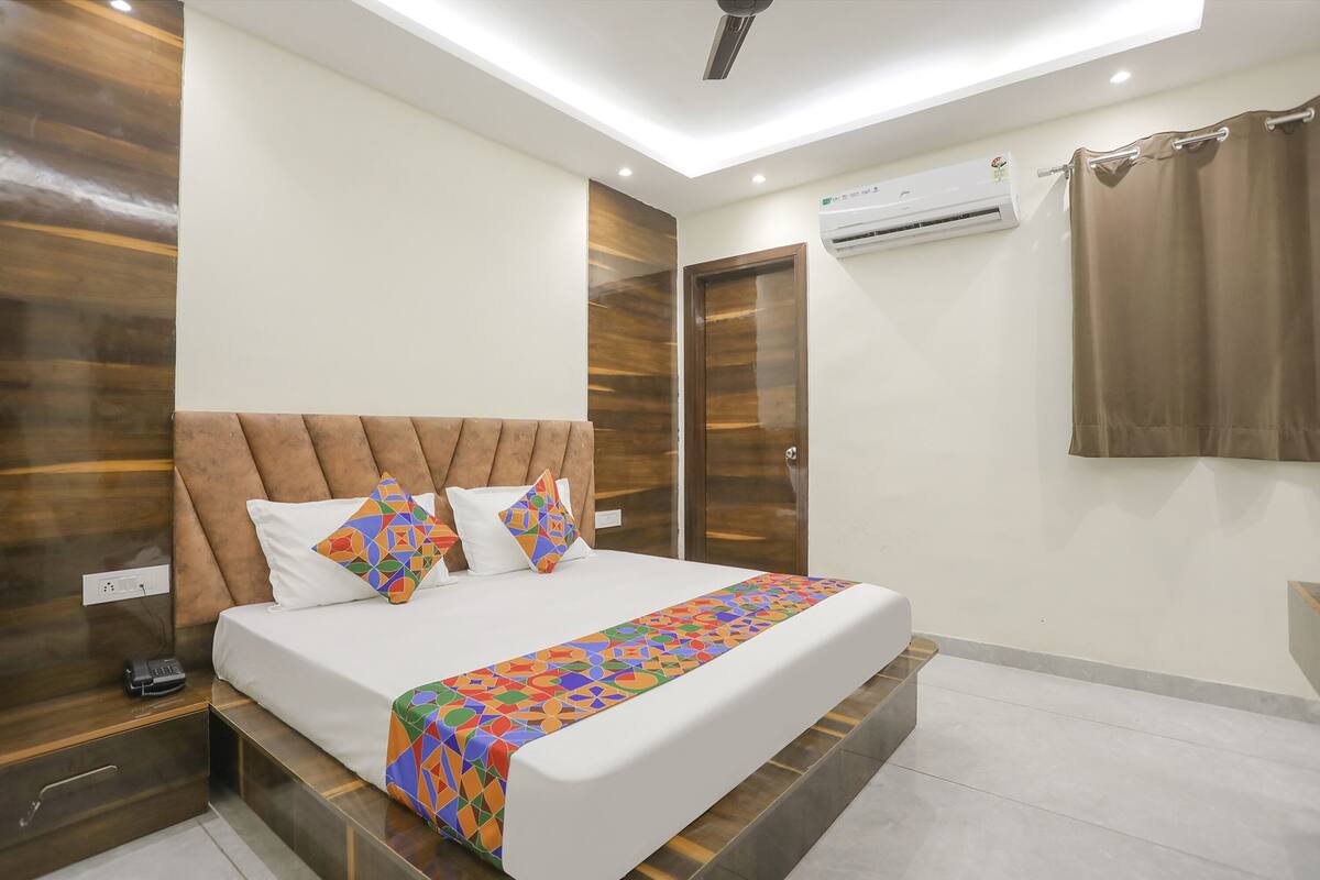 A modern bedroom with a large bed, wooden headboard, and a patterned bedspread.