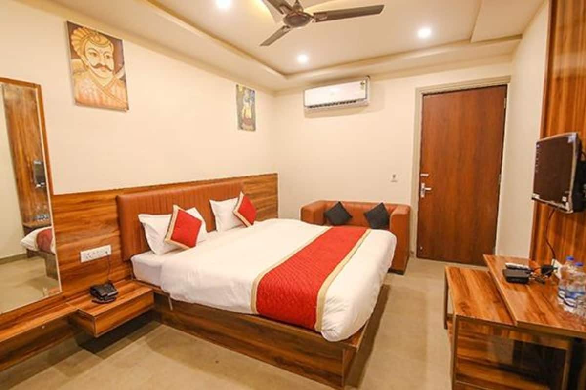 A hotel room with a wooden bed, a desk with a computer, a mirror, and a ceiling fan.