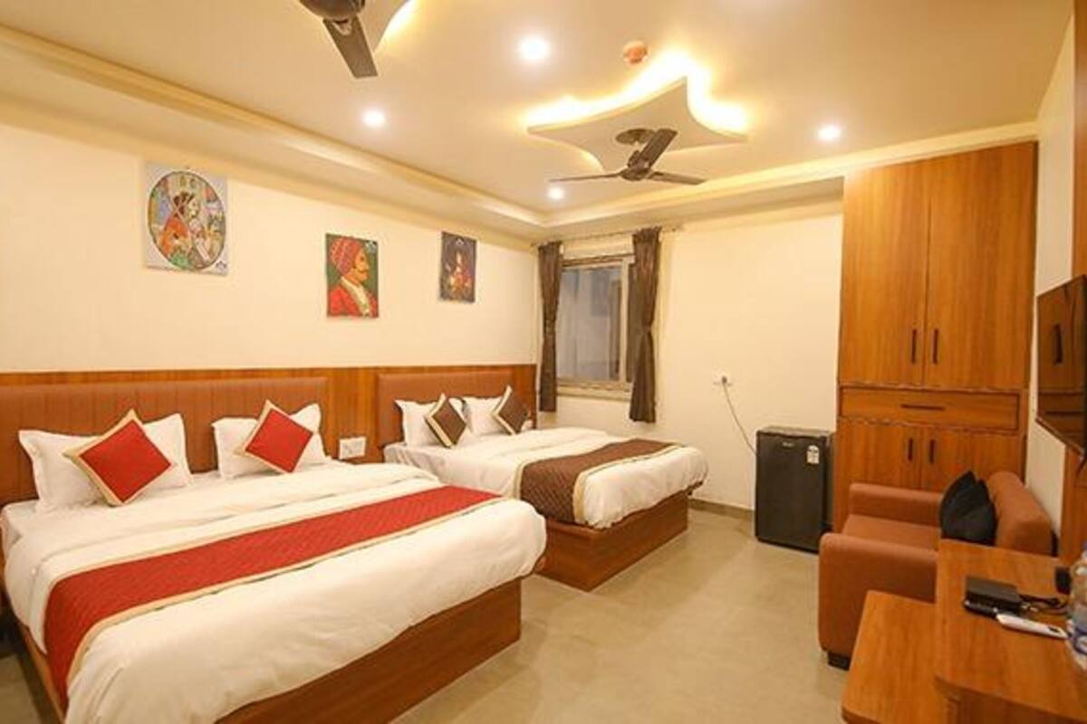 A hotel room with two beds, wooden headboards, a ceiling fan, and a television.