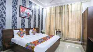 A neatly made bed with a colorful geometric throw, a wooden headboard, and a framed picture on the wall. - Fabexpress Chef'S House (Gurugram)