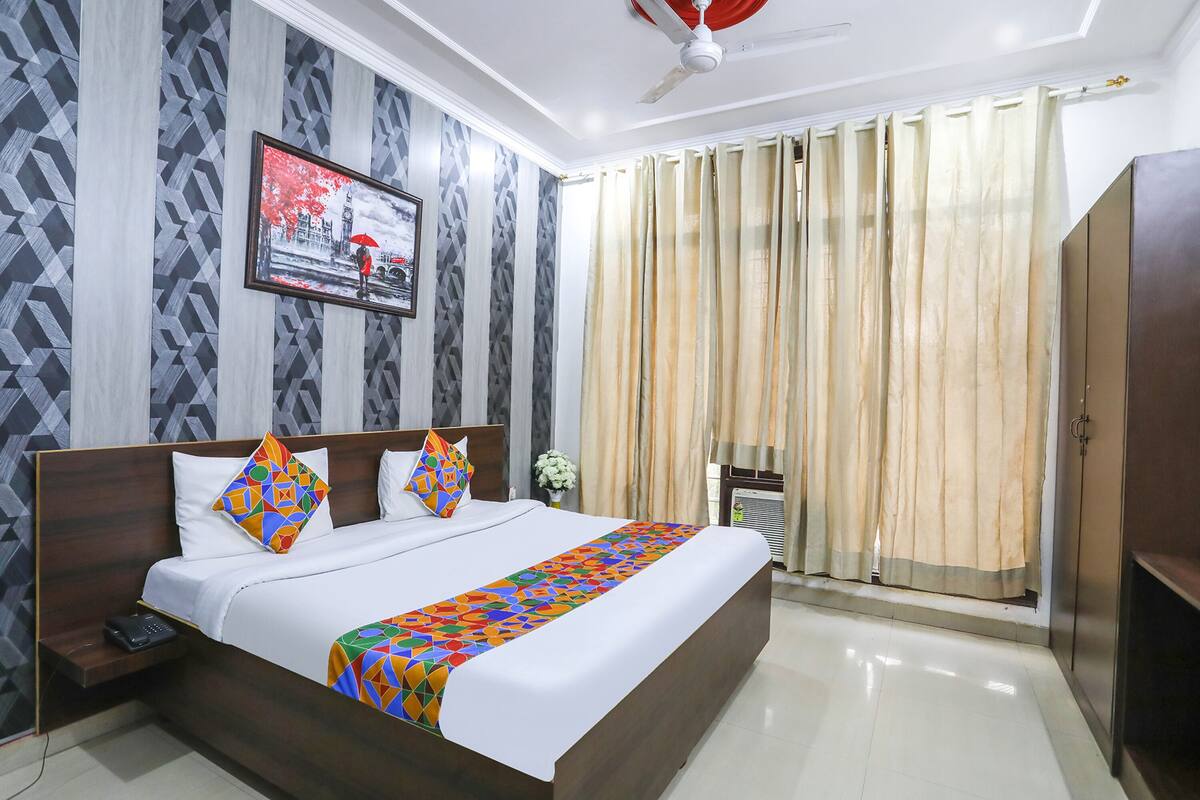 A neatly made bed with a colorful geometric throw, a wooden headboard, and a framed picture on the wall.