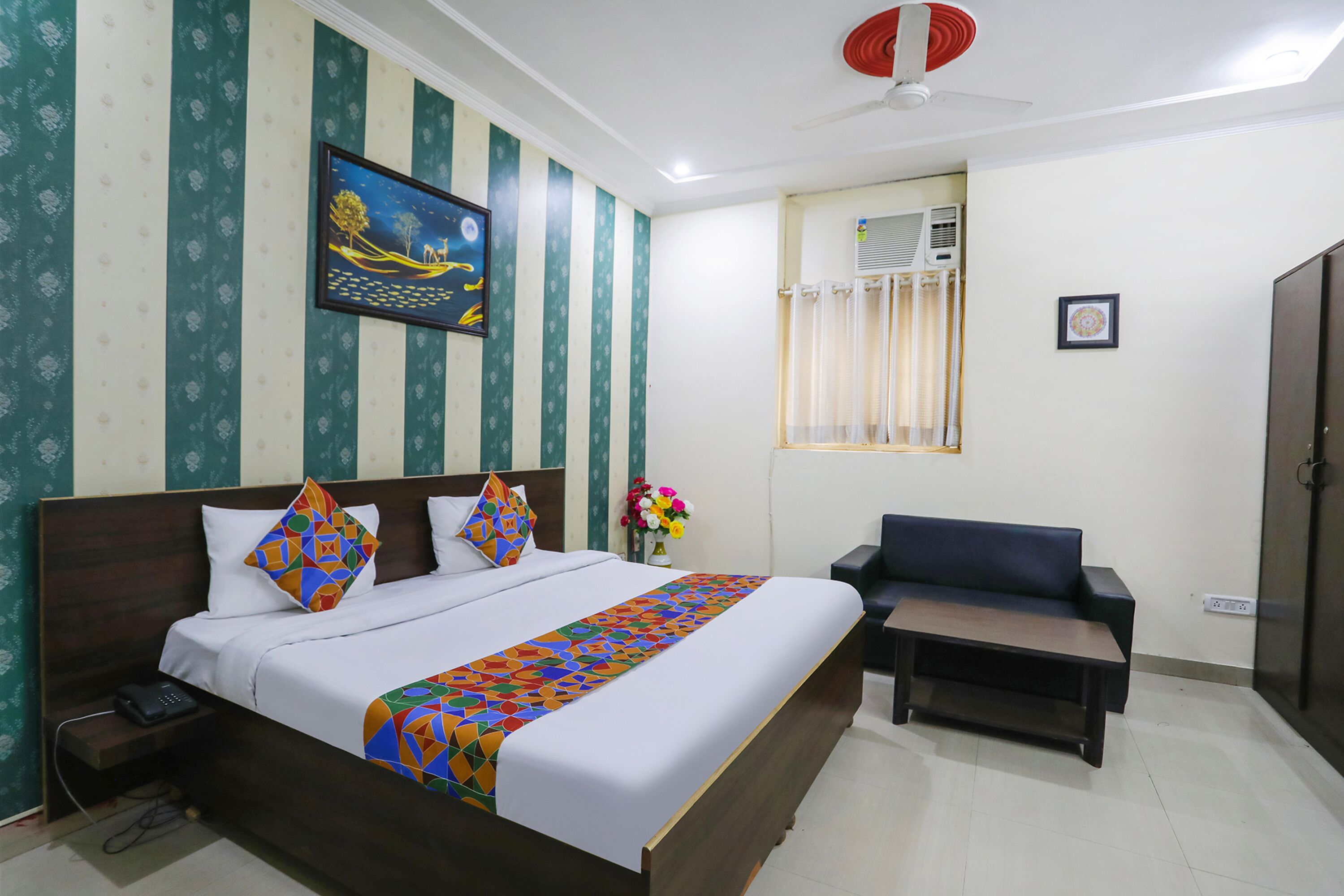 A hotel room with a bed, a chair, a desk, a painting, and a window with curtains.