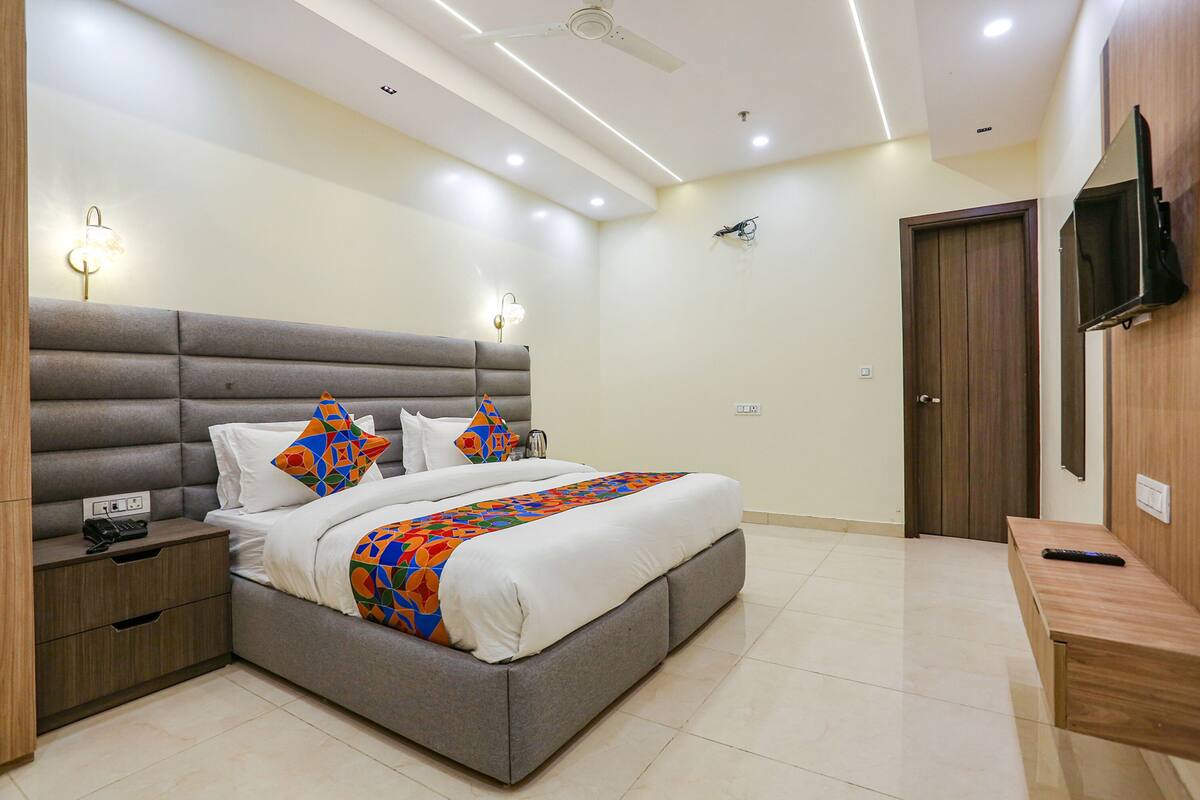A modern bedroom with a large bed, bedside tables, a TV, and a ceiling fan.
