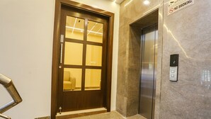 A hotel entrance with a wooden door, an elevator, and a 'No Smoking' sign. - Fabhotel Vishesh Villas (New Delhi)
