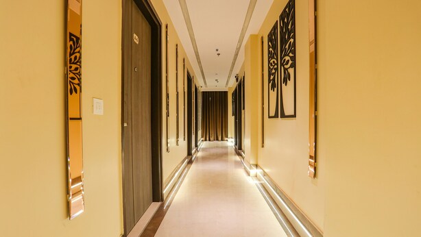 A long, narrow hallway with doors on both sides, leading to rooms. - Fabhotel Vishesh Villas (New Delhi)