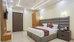 A modern bedroom with a large bed, bedside tables, a wardrobe, and a ceiling fan. - Fabhotel Vishesh Villas (New Delhi)