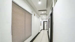 A clean, modern hallway with a tiled floor and a large window with blinds. - Fabhotel Amogh Stay Inn (Nagpur)