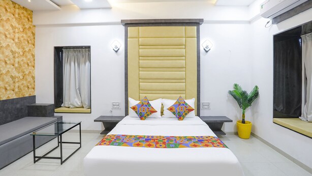 A modern bedroom with a large bed, a glass coffee table, a sofa, and a potted plant. - Fabhotel Amogh Stay Inn (Nagpur)