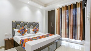 A modern bedroom with a large bed, a nightstand, a wardrobe, and a window with curtains. - Fabhotel 24&7 (New Delhi)
