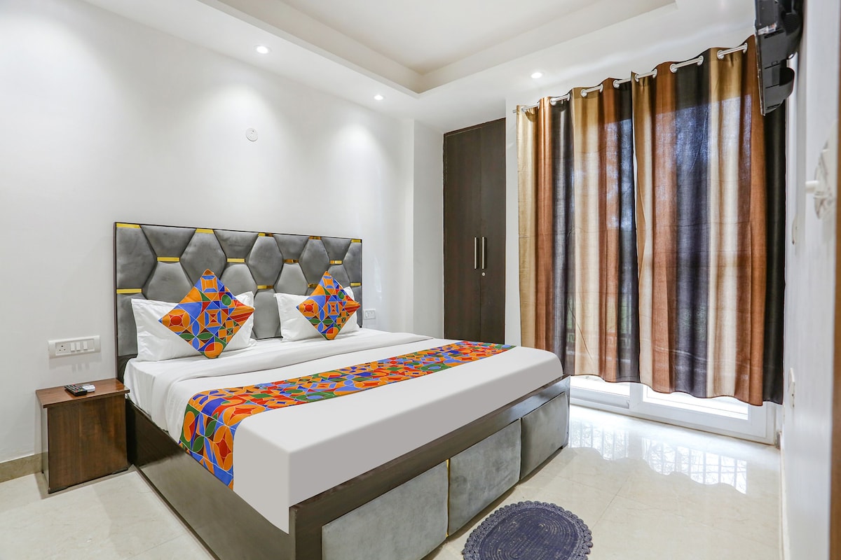 A modern bedroom with a large bed, a nightstand, a wardrobe, and a window with curtains.