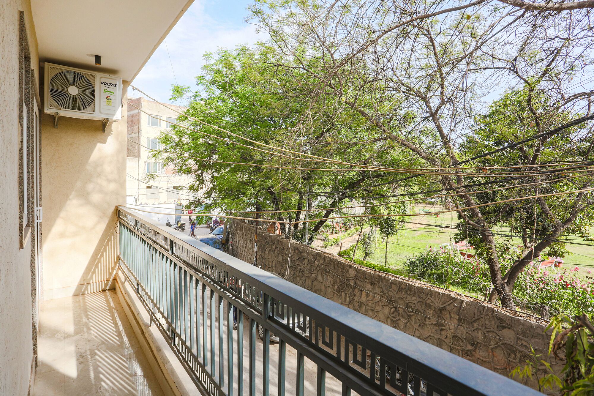 A balcony with a view of a garden and a building in the background.