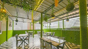A restaurant with green walls, hanging plants, and a patterned floor. - Fabhotel Relax Inn Palace (Haridwar)