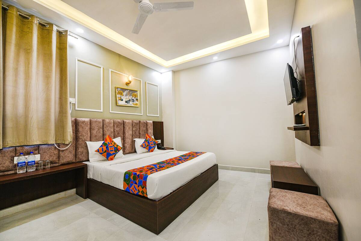 A modern hotel room with a large bed, bedside tables, a flat-screen TV, and a ceiling fan.
