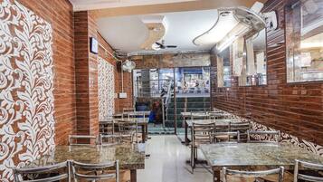 A restaurant with marble-topped tables and chairs, patterned wall designs, and ceiling fans.