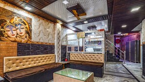 A modern interior with a marble floor, a glass-top coffee table, and a mural of deities on the wall. - Fabhotel Sarwan (Agra)