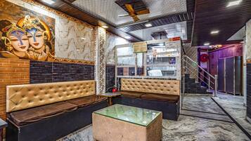 A modern interior with a marble floor, a glass-top coffee table, and a mural of deities on the wall.