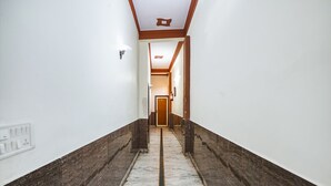 A hallway with marble flooring, white walls, and wooden trim. - Fabhotel Sarwan (Agra)