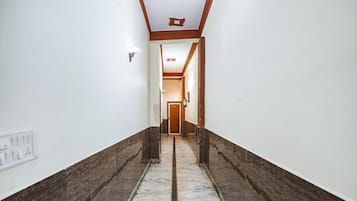 A hallway with marble flooring, white walls, and wooden trim.